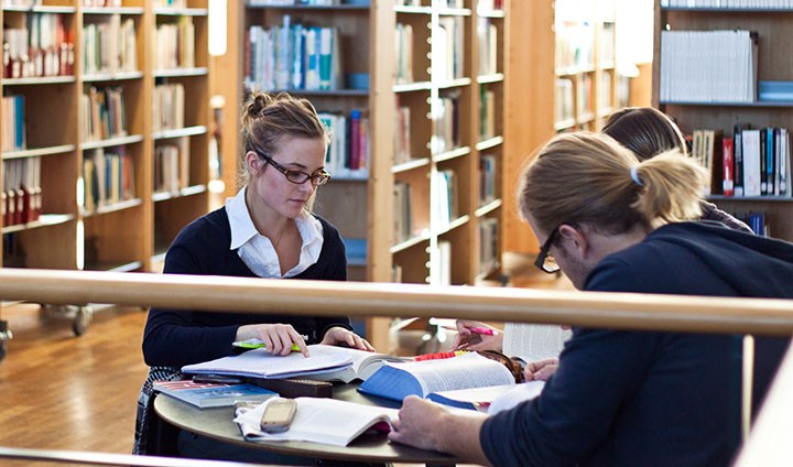Studenter sitter vid ett bord i biblioteket