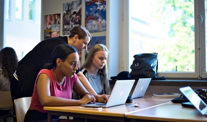 Lärare hjälper elever vid datorer i ett klassrum