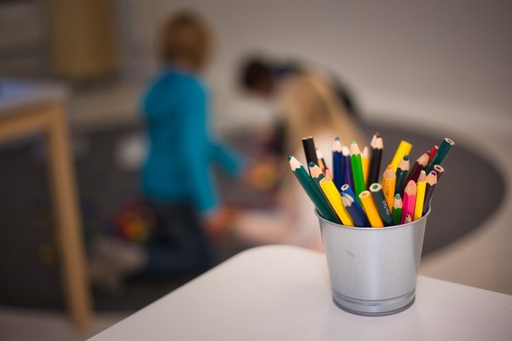 Pennburk i förgrunden, barn i bakgrunden som leker på matta