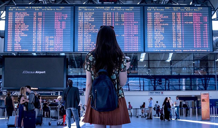 En tjej syns bakifrån tittandes på en avgångstavla på en flygplats