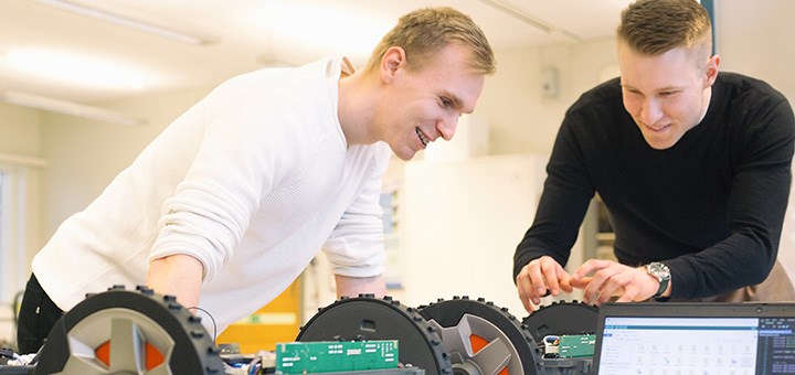 Två studenter arbetar med två robotar.