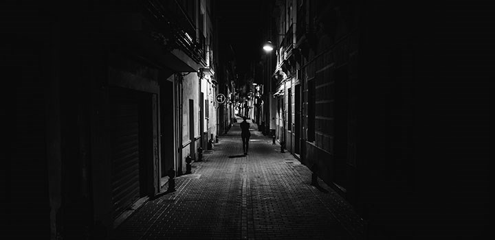 En ensam kvinna går i en mörk gränd.