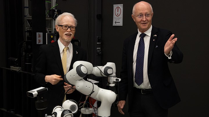 Japans ambassadör och Örebro universitets rektor bakom en robot.