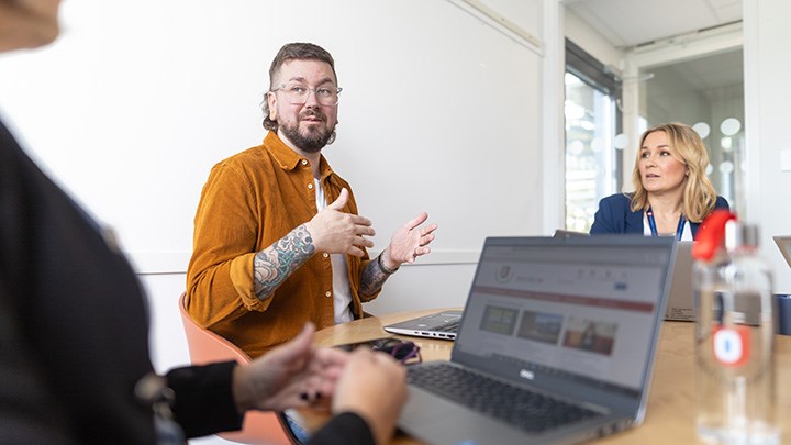 Tre personer vid ett bord. Det står en laptop på bordet.