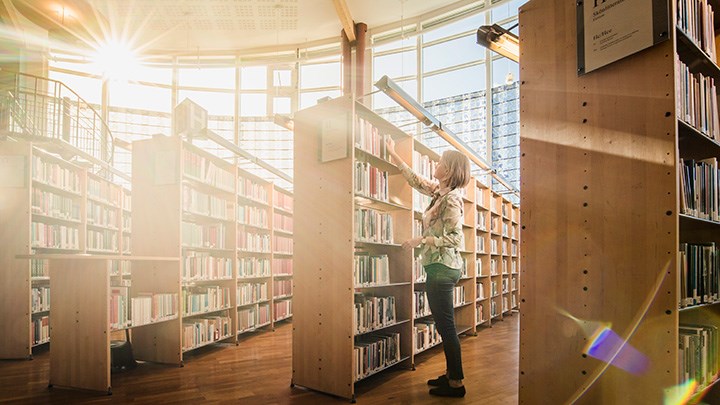 Universitetsbiblioteket och en person som ställer in böcker