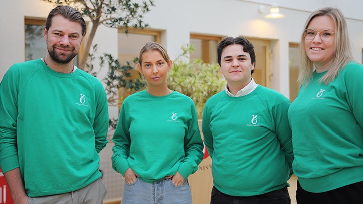 Fyra studenter står med gröna studentkårs-tröjor.