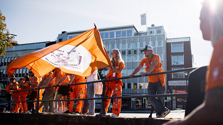 Studenter klädda GIHs färg viftar med en stor flagga i deras färger.